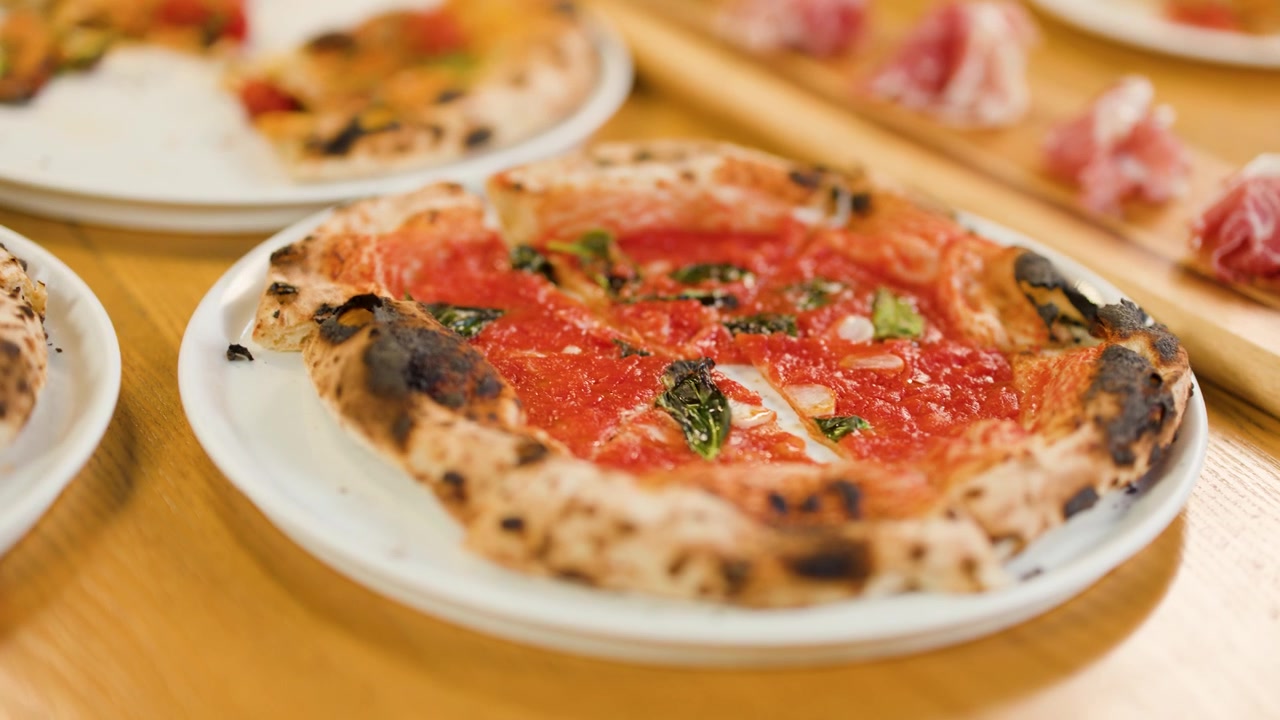 Mani prendono fette di pizza gourmet da piatti bianchi durante una cena sociale al ristorante