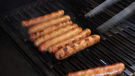 sausages being grilled and turned with tongs