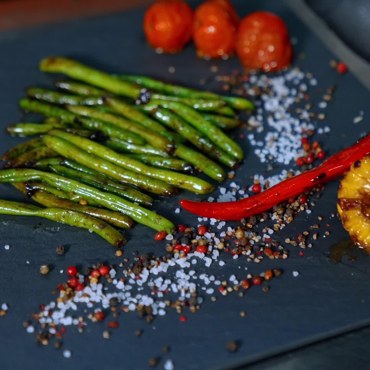 Cook puts the fried vegetables on the black charcuterie board. Serving the dish. Close up. Vertical view