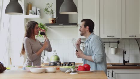 couple using kitchen utensils like microphones singing song dancing indoor