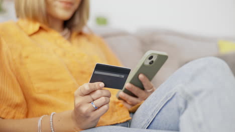 teléfono, tarjeta de crédito y mujer en un sofá haciendo