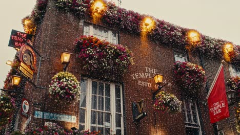 low-angle shot of the temple bar’s brick facade with lights, flowers, and traditional irish signage - ireland