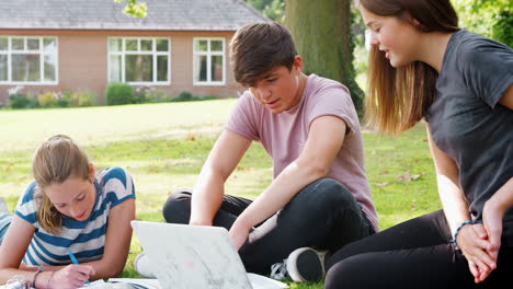 teenage students sitting outdoors and working on project