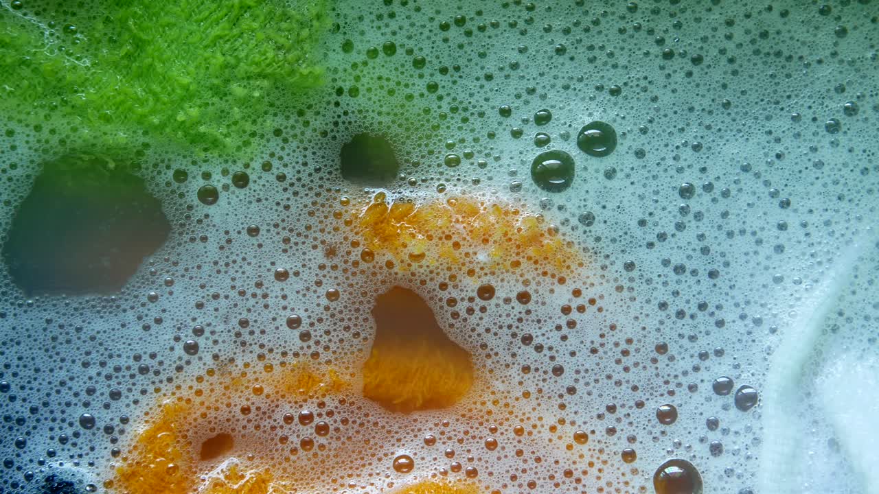 초록색과 오렌지색 천으로 된 수영장에서 비누 거품의 클로즈업