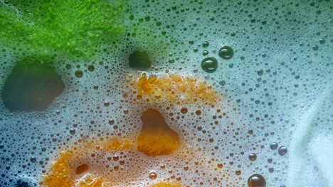 closeup of soapy bubbles in a basin with green and orange cloth