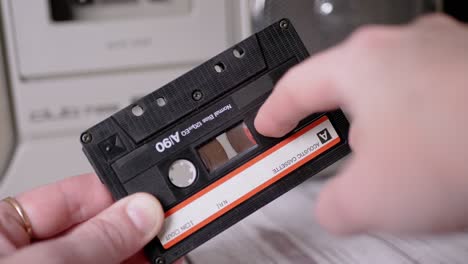 female rewinds a magnetic tape with finger on old vintage audio cassette