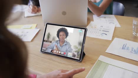 Caucasian-businesswoman-on-tablet-video-call-with-african-american-female-colleague-on-screen