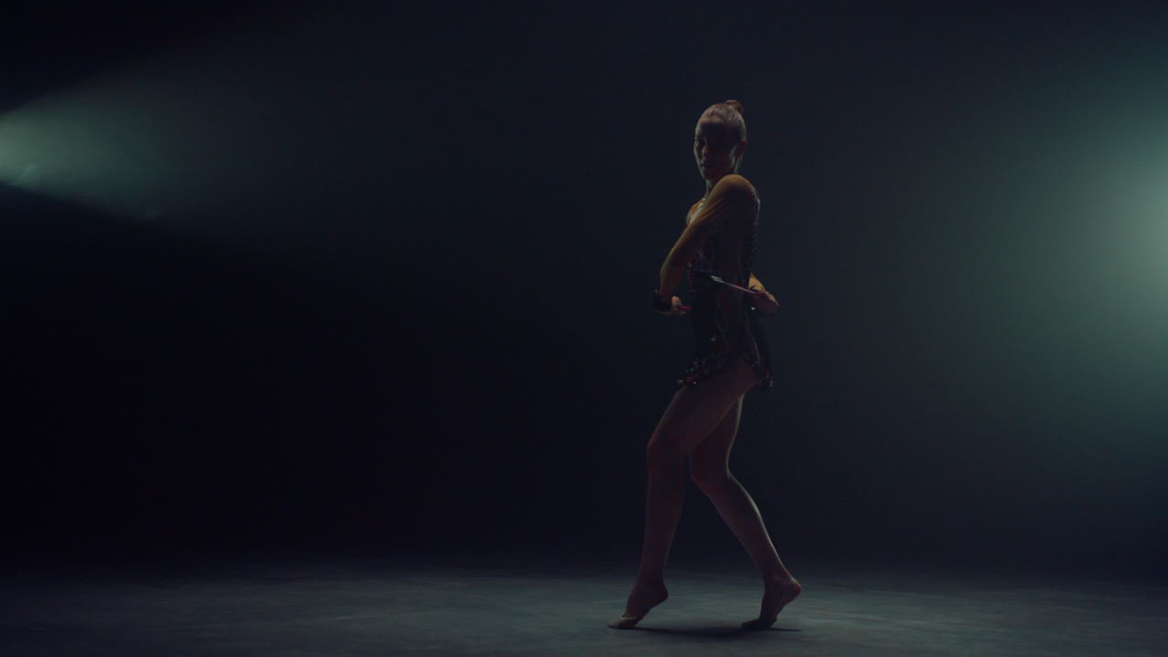 Graceful gymnast exercising with equipment indoors. Woman performing with maces