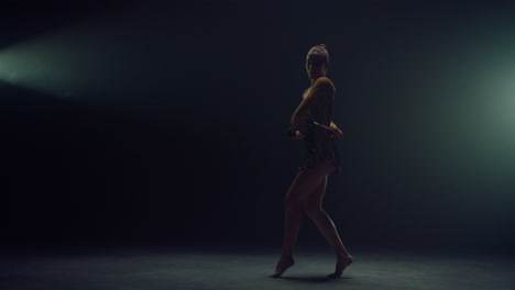 Graceful-gymnast-exercising-with-equipment-indoors.-Woman-performing-with-maces