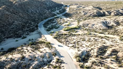 Toma-Aérea-De-Un-Automóvil-Conduciendo-Por-El-Desierto-Del-Parque-Nacional-Joshua-Tree,-Estados-Unidos