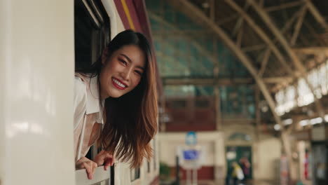 woman looking out train window at station