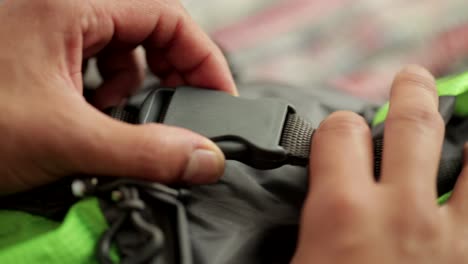 close-up of person's hands undoing rucksack buckle