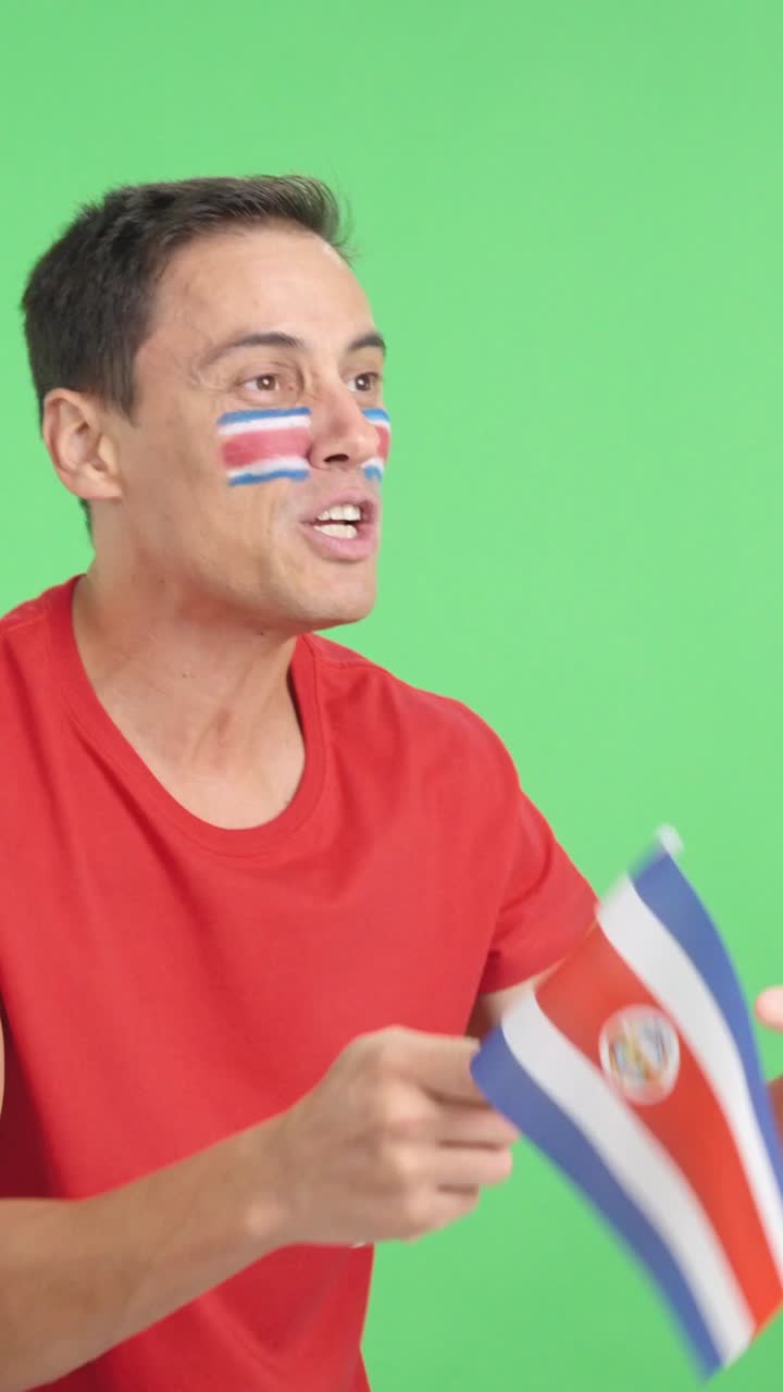 Uomo che fa il tifo per la Costa Rica sventolando una bandiera nazionale e guardando altrove