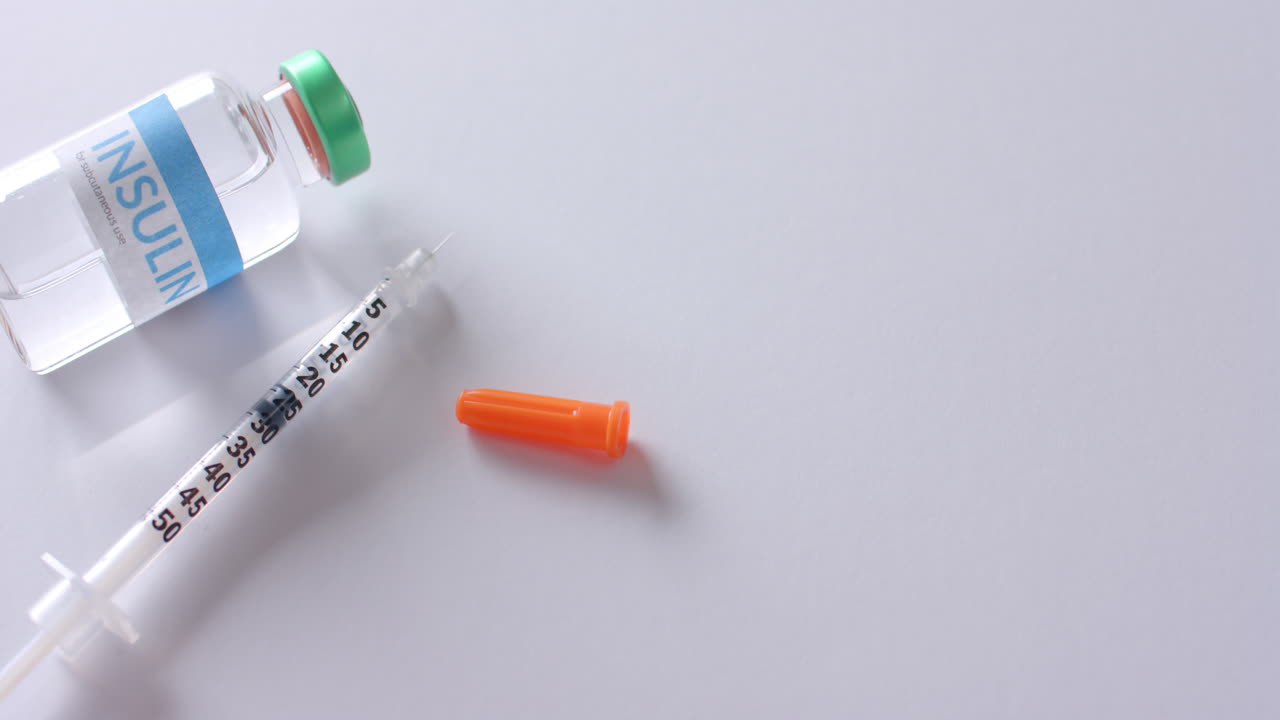 cerrar el vial de insulina y la jeringa sobre un fondo blanco con espacio de copia, cámara lenta.