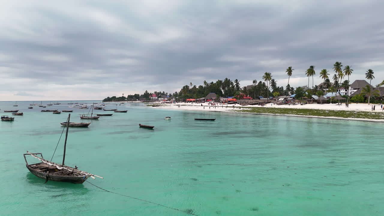 sobrevuelo aéreo de las aguas claras de la isla de zanzíbar, con playa de arena y barcos estacionados