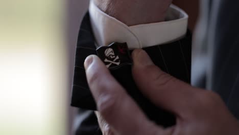 primer plano de un novio ajustando sus gemelos de temática pirata mientras se prepara para el día de su boda
