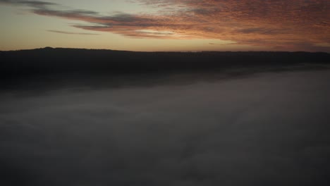 aerial of the most amazing play of light at sundown: red and orange sunset over fog mist