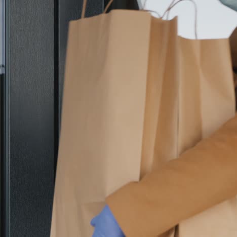 a woman with packets of groceries in her hands walks through the door of her house