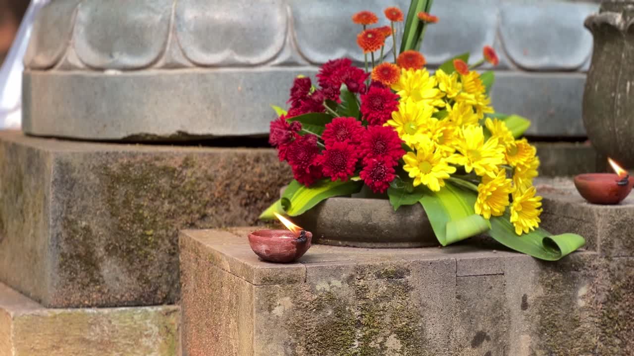 flores y velas en el pedestal de una estatua de buda en el día de vesak