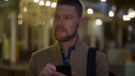 retrato de un joven hombre de negocios pensativo que usa un teléfono inteligente enviando mensajes de texto navegando en línea enviando mensajes de texto en teléfono móvil en la ciudad por la noche en cámara lenta