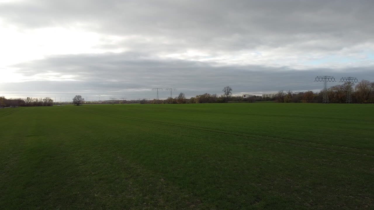 Drone flying over green field with power poles with Autobahn in background