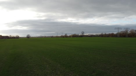 drone flying over green field with power poles with autobahn in background