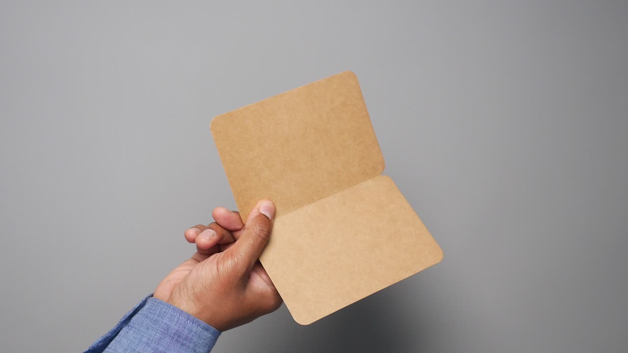 Hand holding a blank brown paper card