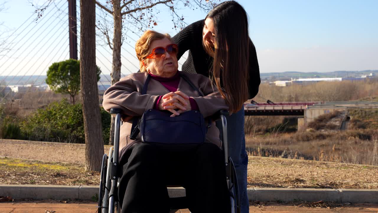 Grandmother and granddaughter laugh together in sunny park conversation