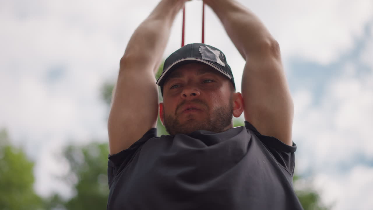 Hombre con gorra relajándose al aire libre con los brazos tras la cabeza; golfista descansando tras el swing; cielo y árboles de fondo; luz cálida del sol; polo informal; barba; expresión contemplativa; parque; ambiente veraniego; naturalidad.