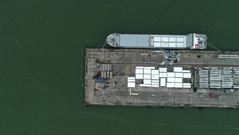 aerial view of loading dock shipping containers with boat anchored waiting to be loaded