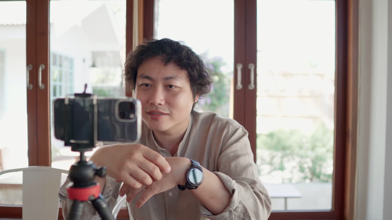 아시아인 남자가 앉아서 스마트폰과 대화하고 있습니다.