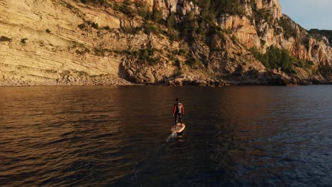 toma aérea siguiendo a alguien en una tabla de surf eléctrica recorriendo la escarpada costa de españa
