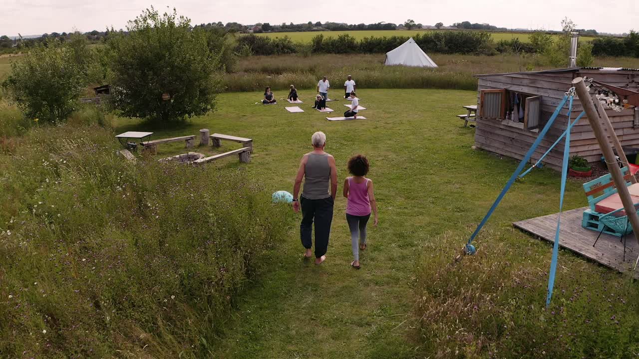 tomada con avión no tripulado del maestro que lidera un grupo de hombres y mujeres maduros en clase en un retiro de yoga al aire libre