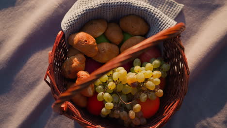 picnic basket full of fruit, bread, and rolls