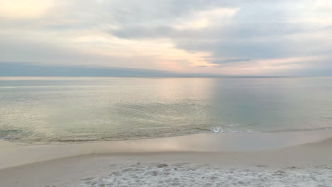 ocean waves gently hit the shore at sunset