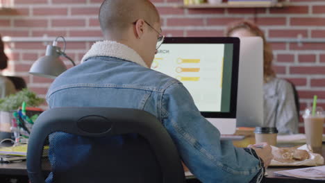 young business student man using computer working brainstorming marketing project writing study notes browsing online research in modern office