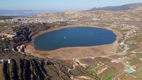 Aerial-view-of-terraced-hill-with-homes-and-trees-above-crater-Lake-Ram,-Israel