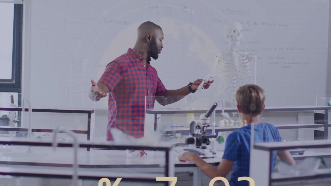 Teacher gesturing as boy adjusting microscope causing moving charts over skeleton in science lab