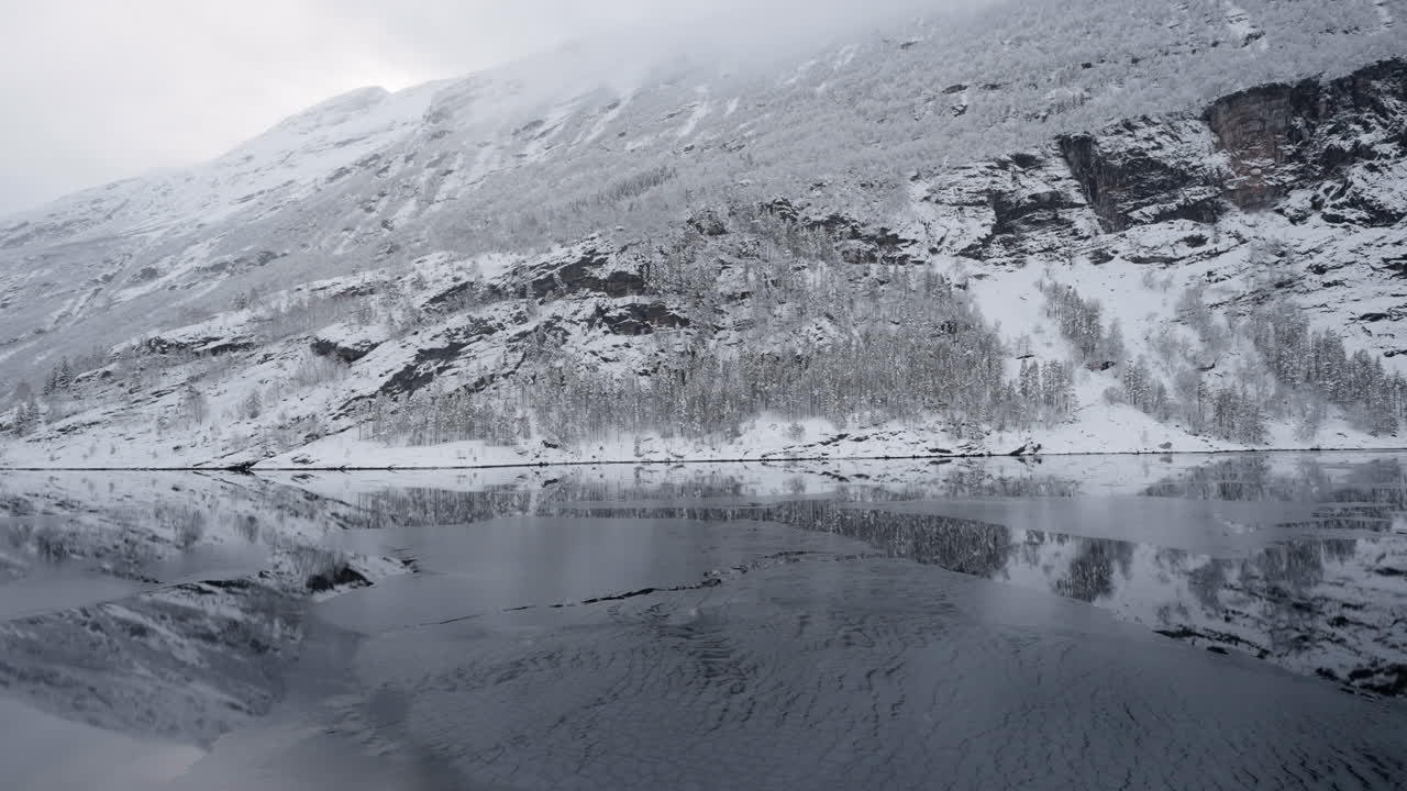 pov imágenes de un paseo en barco a través de geirangerfjord, noruega, destacando la belleza tranquila del fiordo y las montañas nevadas circundantes en invierno
