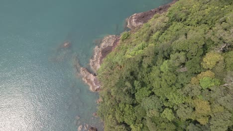 aerial, birds eye view of tropical rocky granite ocean coastline with lush tropical forest vegetation on a island