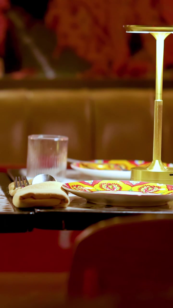 Table transforms from decorated to cleared, under warm lighting in vibrant restaurant environment, static camera