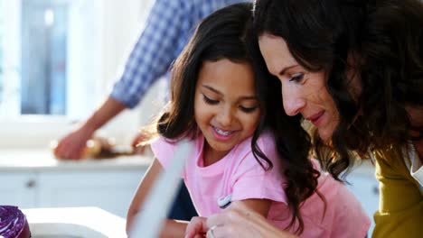 Mother-and-daughter-preparing-salad-in-kitchen