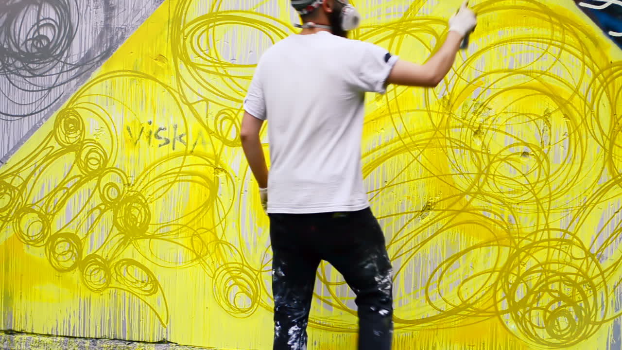 O artista desenha grafite em uma cerca. Desenho abstrato