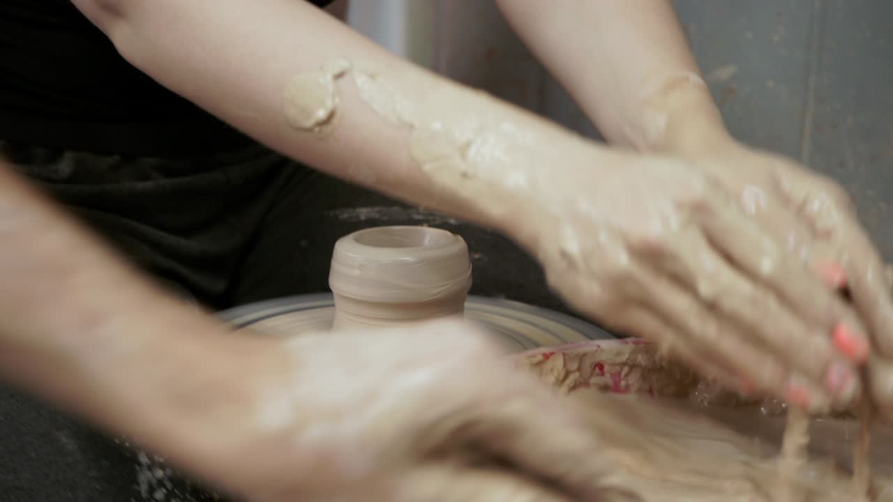 un alfarero enseña a una mujer a hacer platos de arcilla. un hombre toma las manos de una mujer