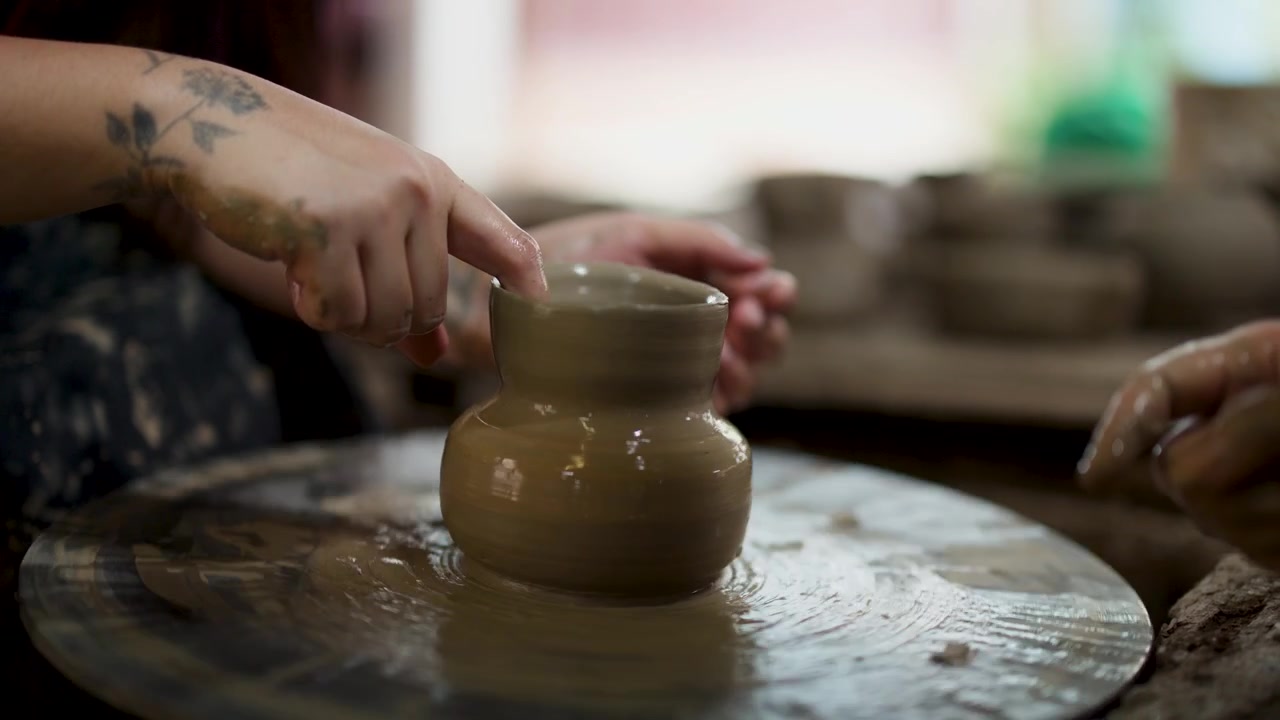 Artigiani modellano con le dita un vaso di argilla al tornio in un laboratorio in Thailandia.