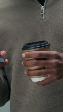 man using phone and drinking coffee