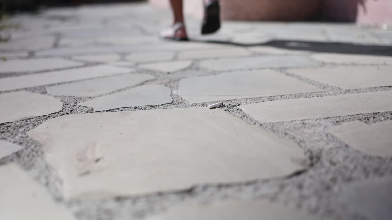 A person's feet wearing sandals on a stone pavement