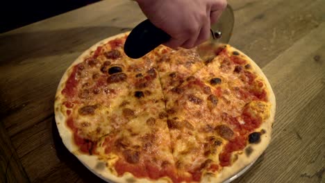 closeup hand of chef baker cutting pizza