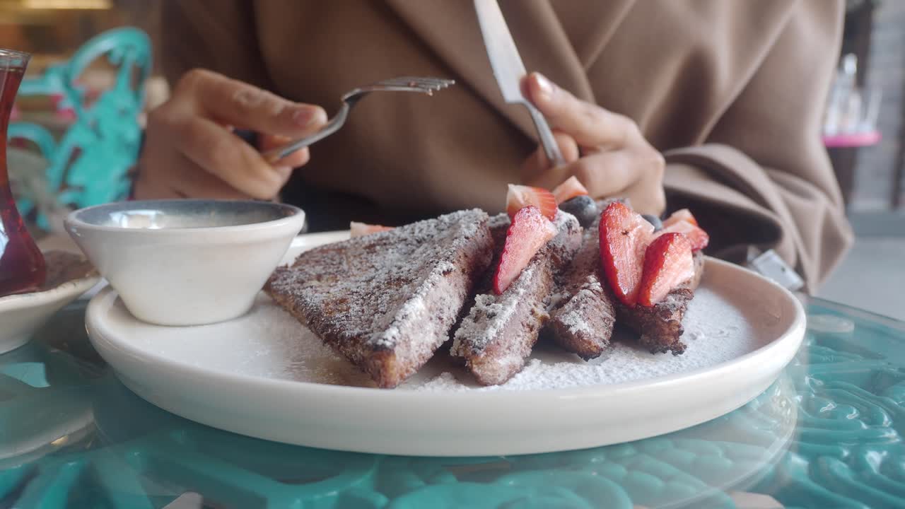 Persona che taglia del delizioso French Toast con fragole e mirtilli