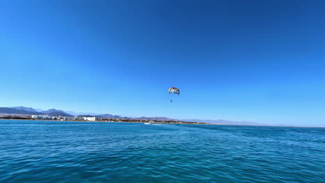 person parasailing near tropical coastline, motion view